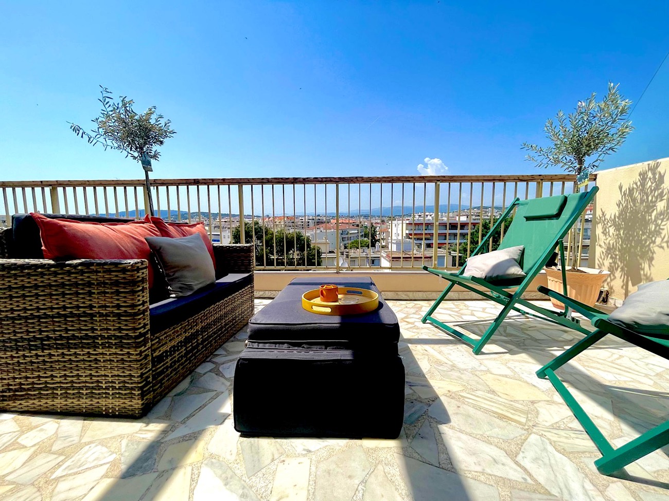 Terrasse ensoleillée avec salon de jardin et vue sur la Riviera cannoise